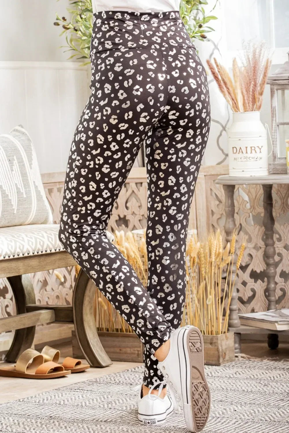 Woman wearing high-waisted black and white leopard print leggings in cozy indoor setting