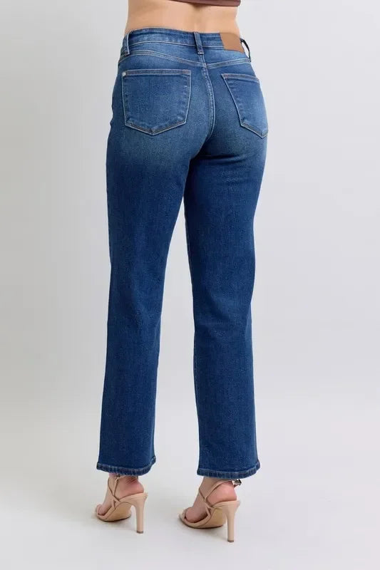 Back view of straight-leg blue jeans with raw hem, worn with nude heeled sandals.