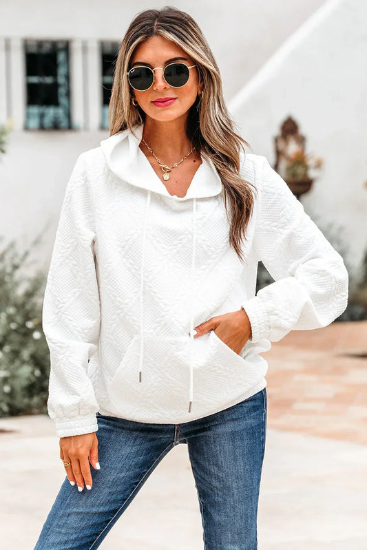 Woman wearing a quilted white pullover hoodie with relaxed fit and blue jeans outdoors