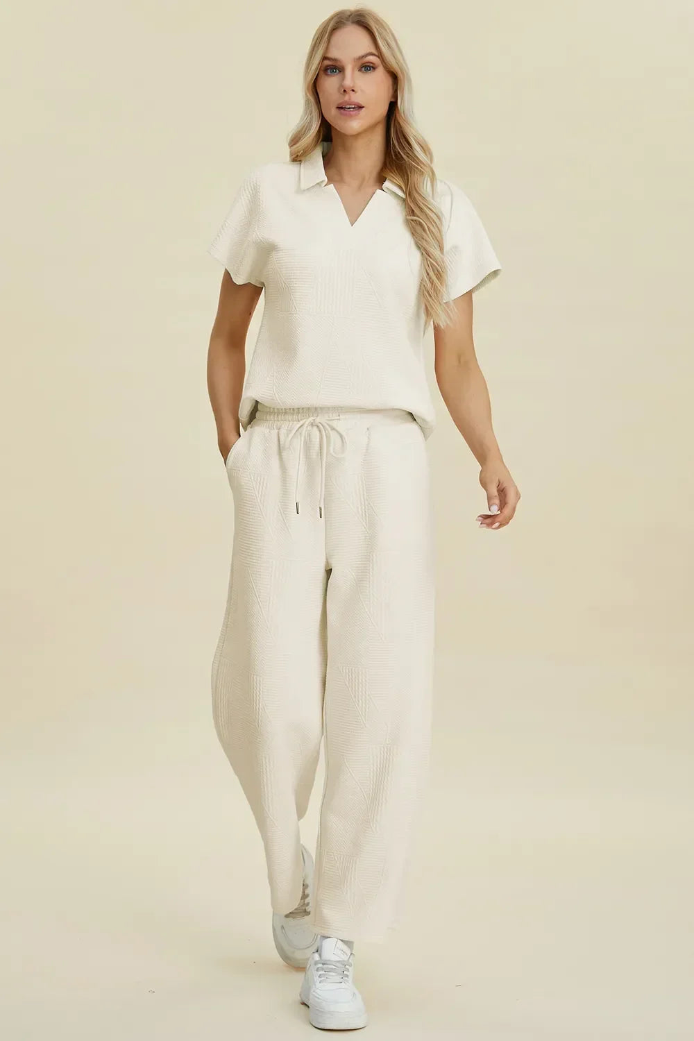 Woman wearing a cream textured short sleeve top and drawstring wide leg pants set