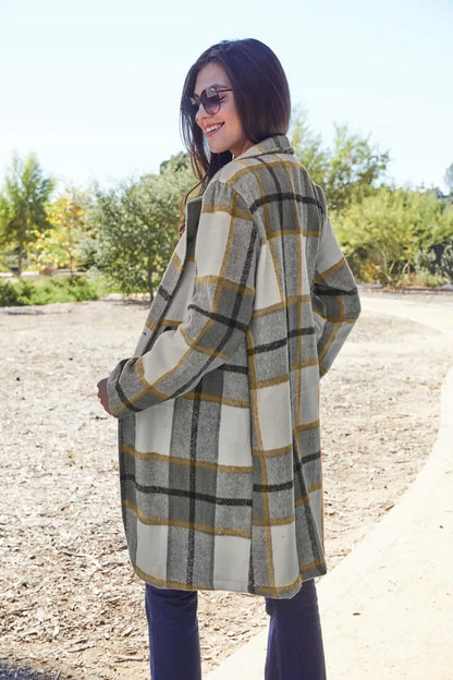 Woman outdoors wearing oversized plaid coat with grey, white, and yellow stripes