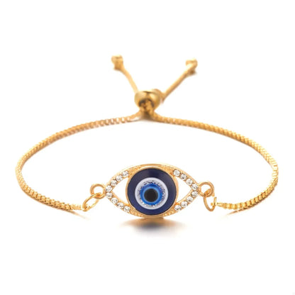 Gold adjustable bracelet with blue evil eye charm and clear crystal accents, isolated on white