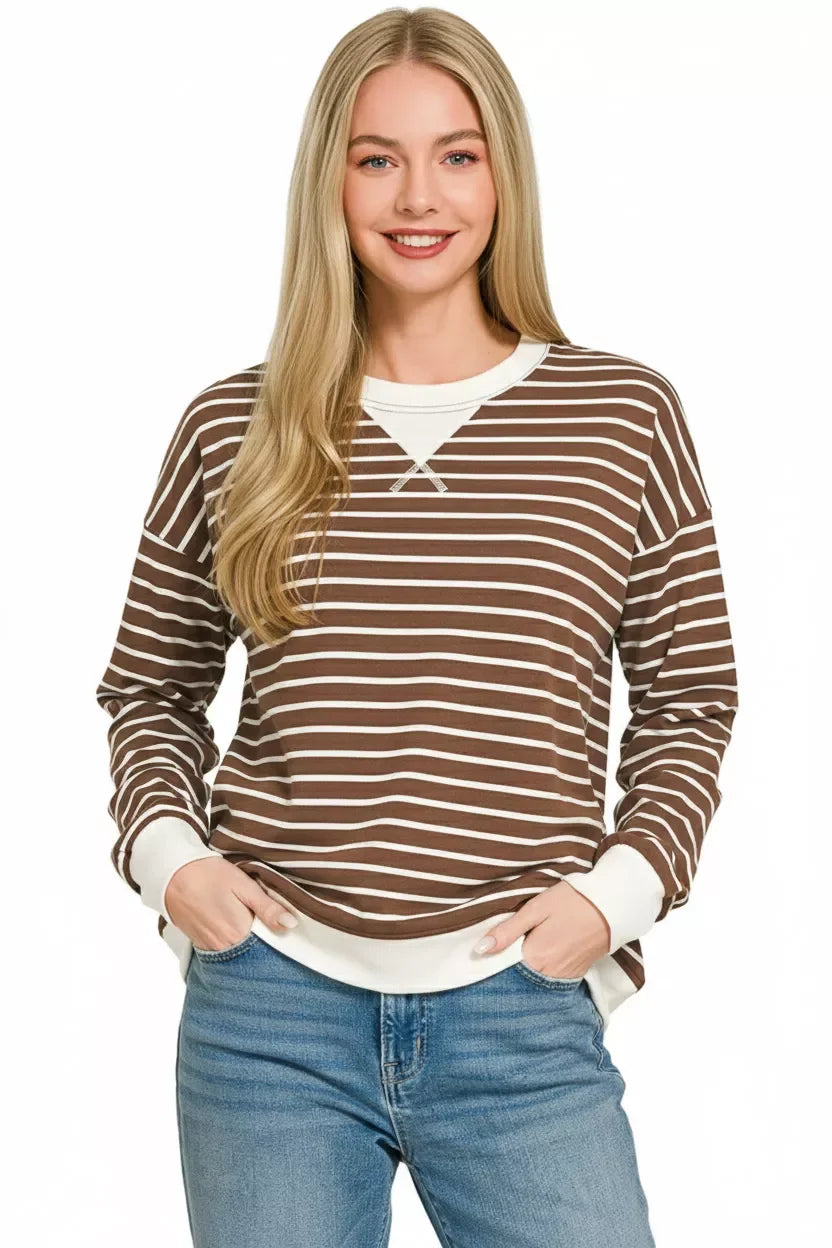 Woman wearing brown and white striped long sleeve top with relaxed fit and blue jeans