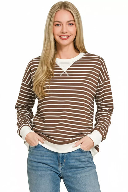 Woman wearing brown and white striped long sleeve top with relaxed fit and blue jeans