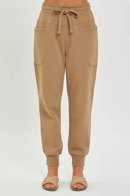 Women’s tan jogger pants with drawstring waist, front pockets, and cuffed ankles