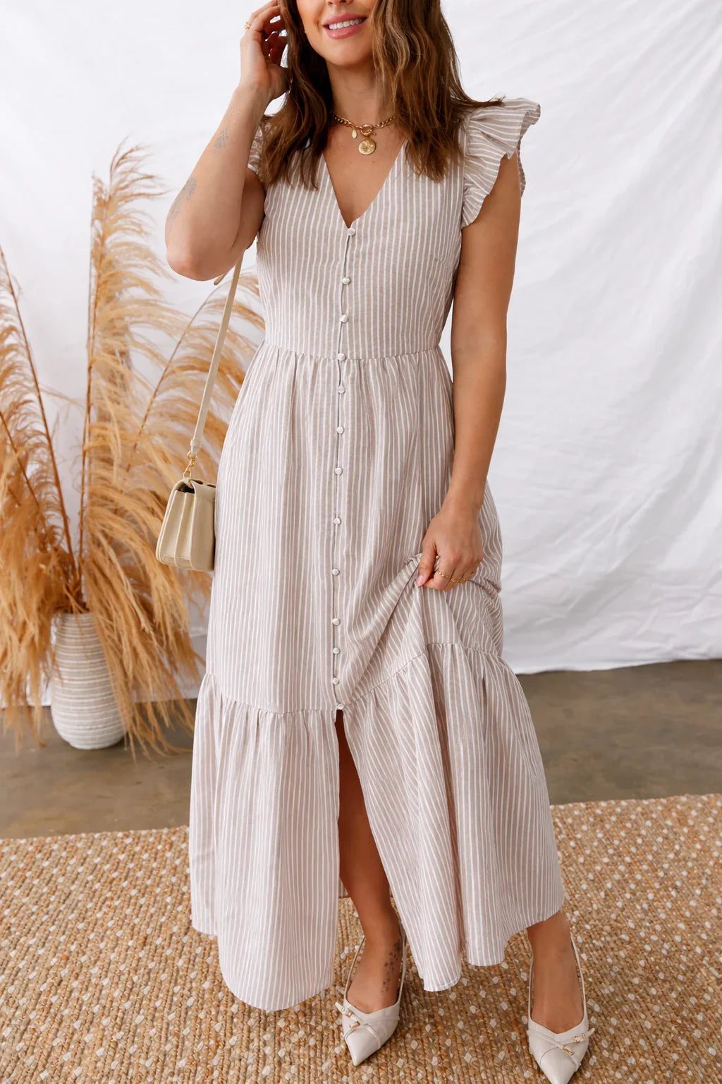 Woman wearing a striped, button-front midi dress with flutter sleeves and neutral heels