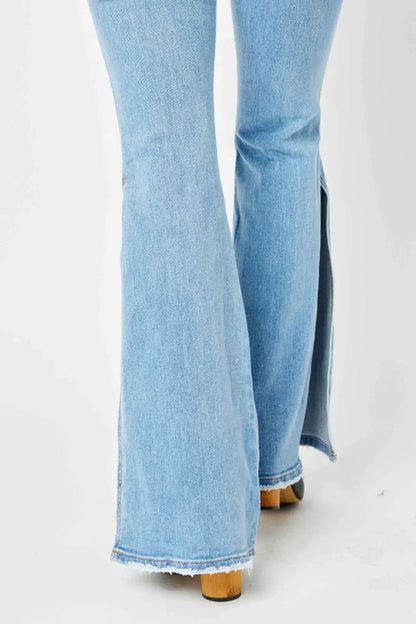 Light wash flare jeans with side slits and raw hem, shown from the back