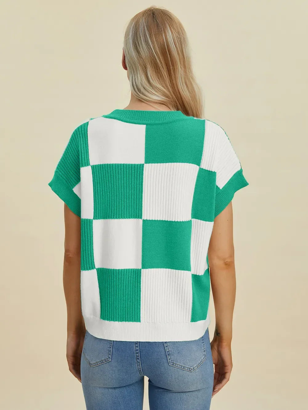Woman wearing a green and white checkered knit short-sleeve sweater with blue jeans