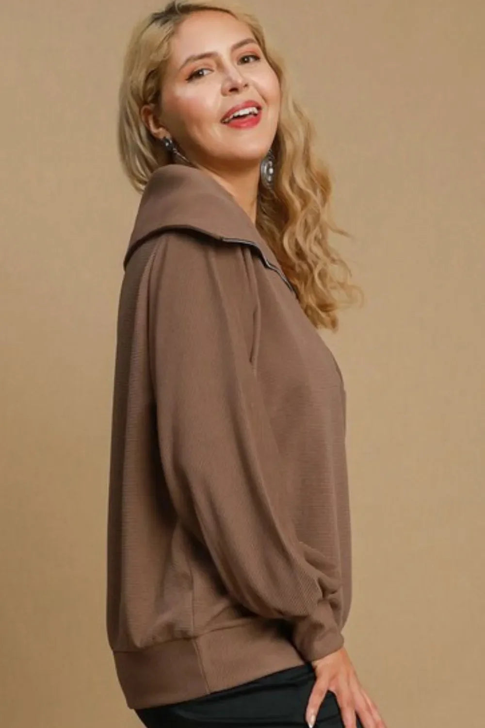 Woman wearing a taupe pullover top with relaxed silhouette and oversized collar