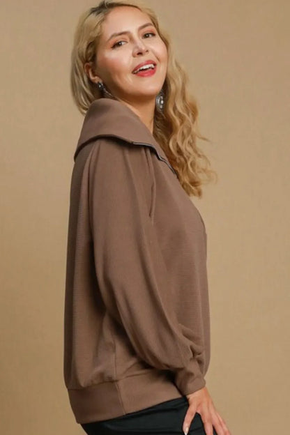 Woman wearing a taupe pullover top with relaxed silhouette and oversized collar