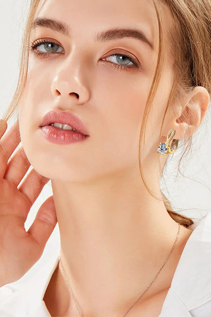 Closeup of woman wearing gold and crystal stud earrings, showcasing minimalist jewelry style