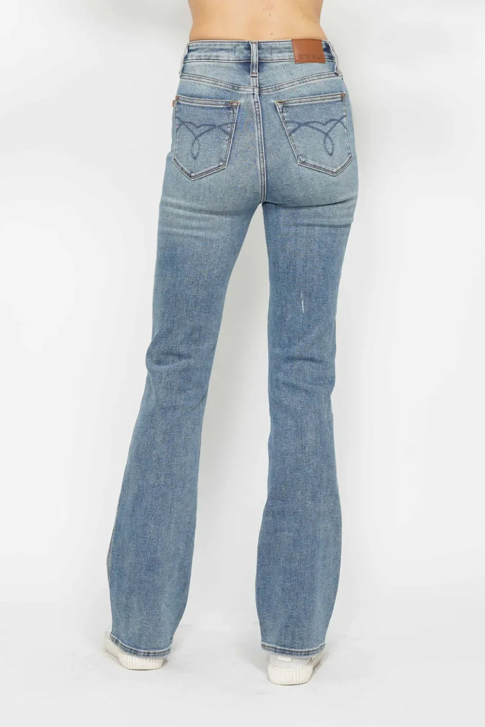 Back view of a woman wearing light blue high-rise flared jeans with minimal distressing.