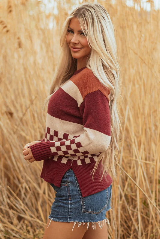 Woman in a colorblock knit sweater with checkered detail and denim shorts outdoors.