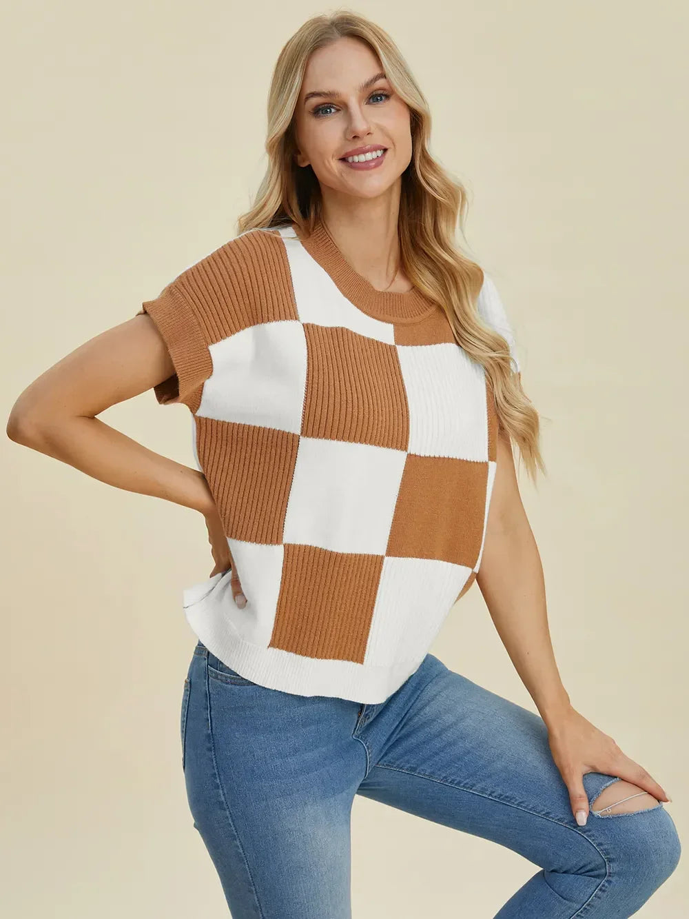 Woman wearing a brown and white checkered knit short-sleeve sweater with blue jeans