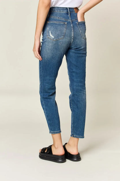 Woman wearing high-waisted blue jeans with back pockets and black sandals