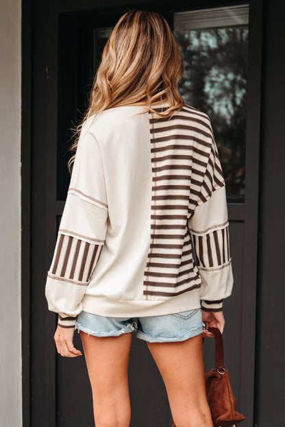 Woman wearing cream and brown striped pullover with denim shorts, back view