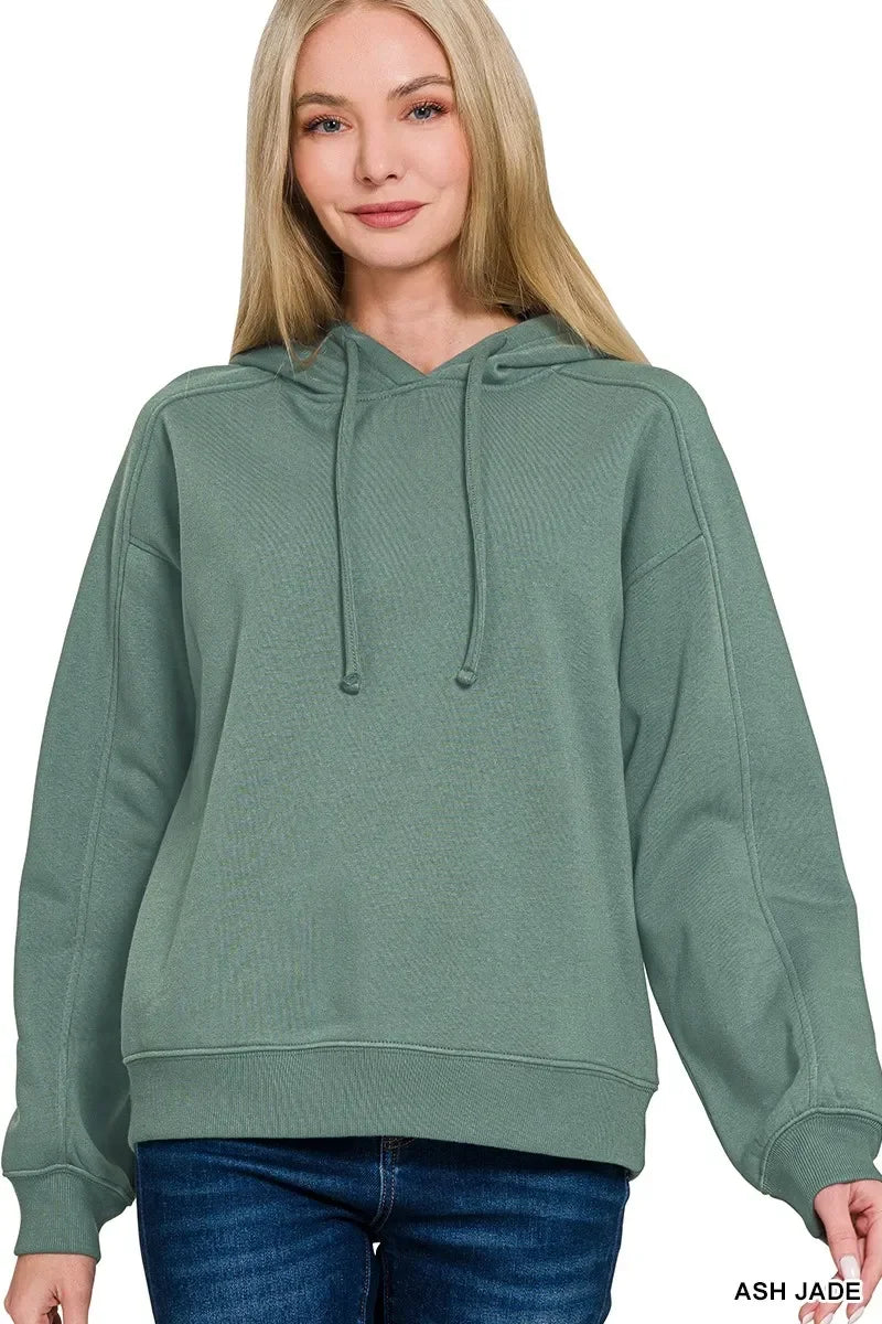Woman wearing relaxed fit ash jade green hoodie with drawstrings and blue jeans