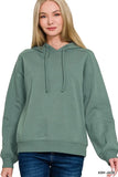 Woman wearing relaxed fit ash jade green hoodie with drawstrings and blue jeans