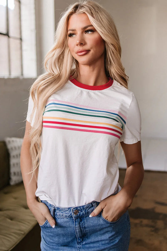 Woman wearing a white t-shirt with colorful stripes and blue jeans in a bright room