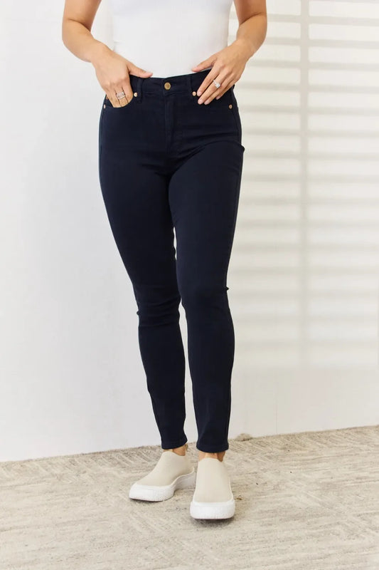 Woman wearing dark high-rise skinny jeans and slip-on sneakers on a textured rug