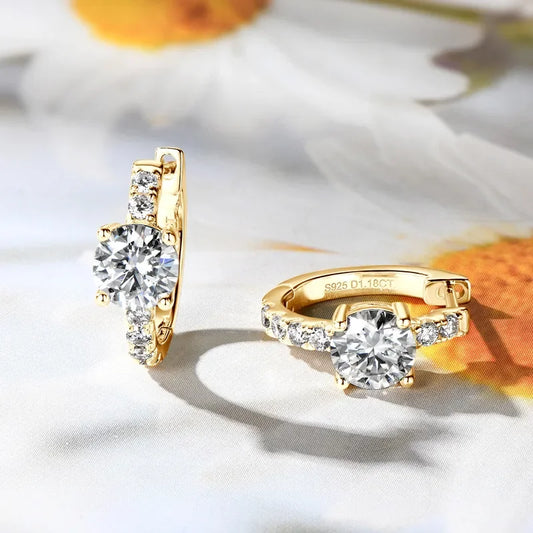 Gold hoop earrings with round-cut cubic zirconia stones displayed on floral background