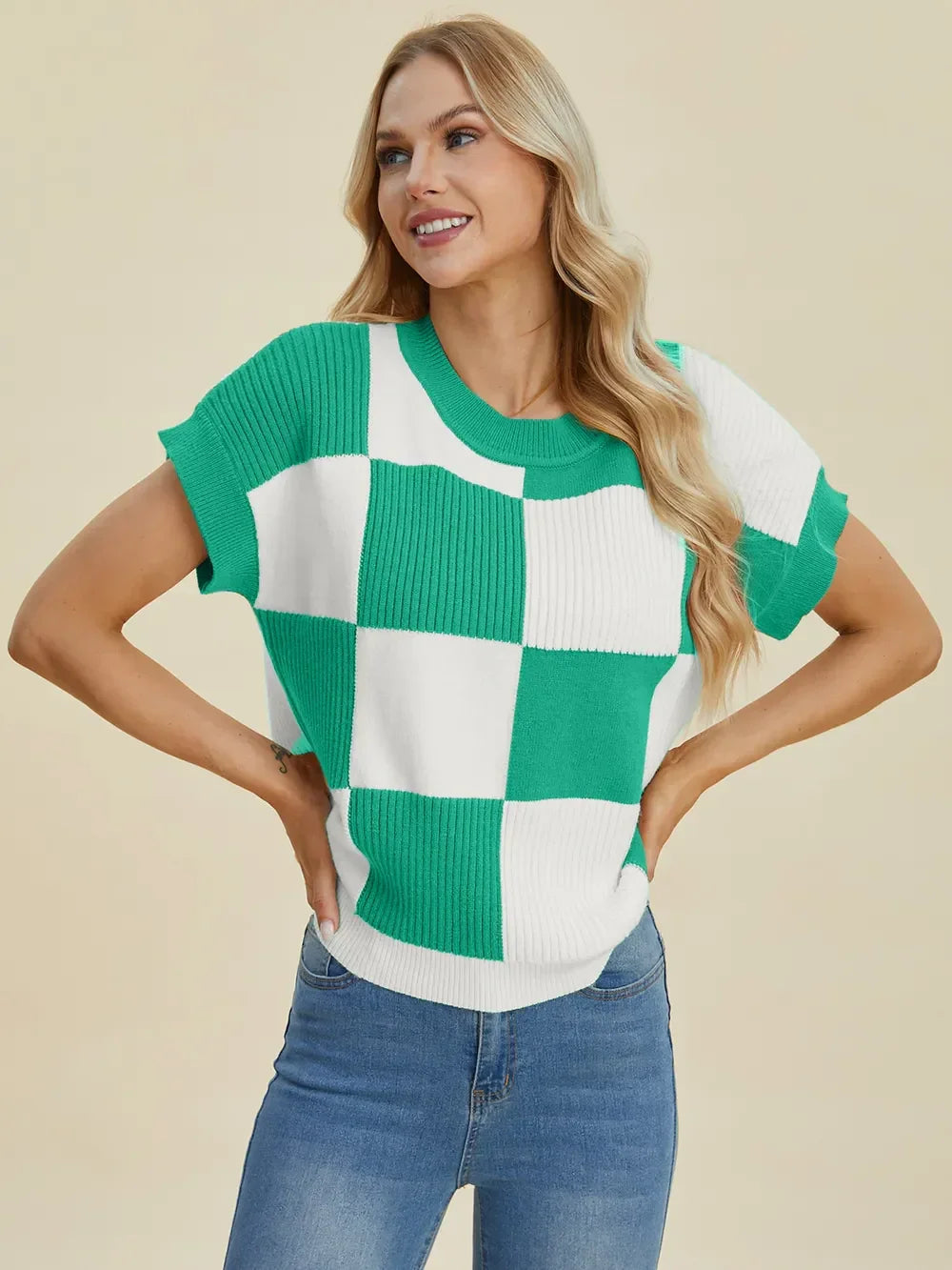 Woman wearing a green and white checkered knit sweater top with short sleeves and blue jeans
