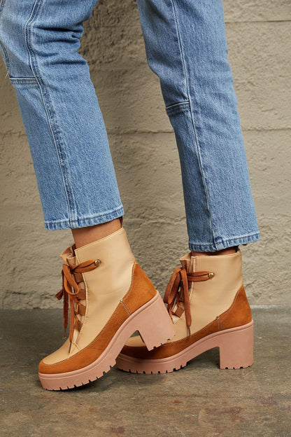 Tan and brown lace-up platform boots paired with cropped blue jeans on concrete floor