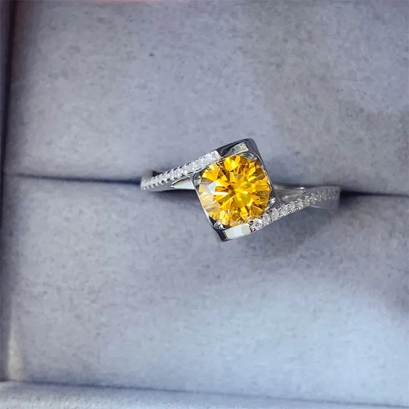 Silver ring with a brilliant yellow gemstone centerpiece and pavé diamond band in a jewelry box.
