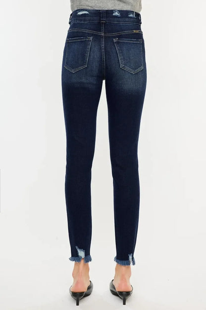 Back view of dark wash skinny jeans with raw frayed hems and distressing detail