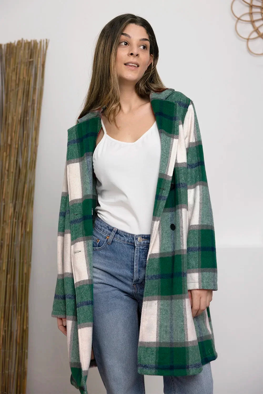 Woman in green plaid coat, white tank top, and blue jeans, modern casual outfit