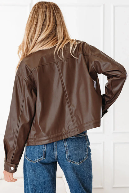 Woman in brown faux leather jacket and blue jeans, seen from the back indoors