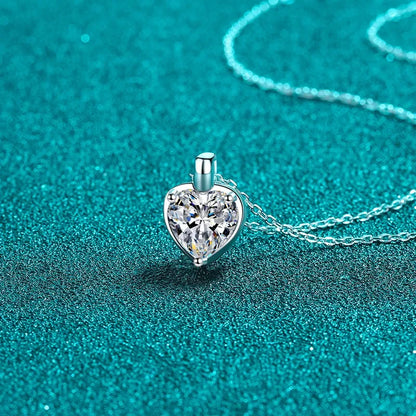 Heart-shaped crystal pendant necklace on a silver chain against teal background