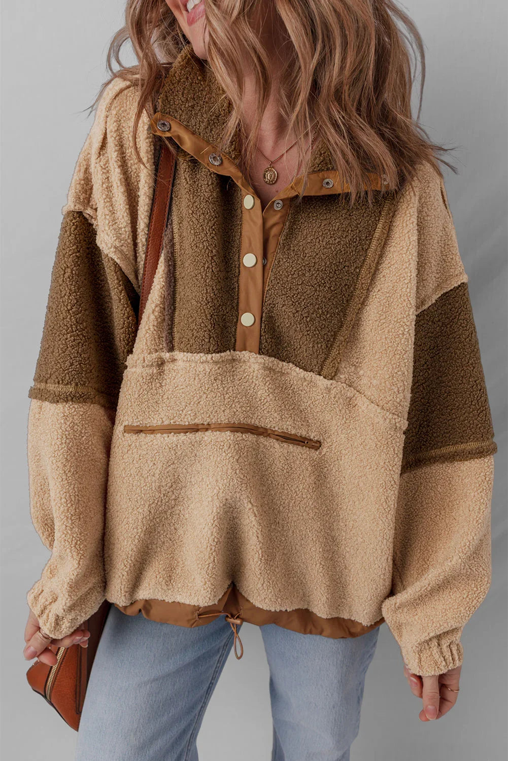 Woman wearing a colorblock sherpa fleece pullover with snap buttons and light wash jeans