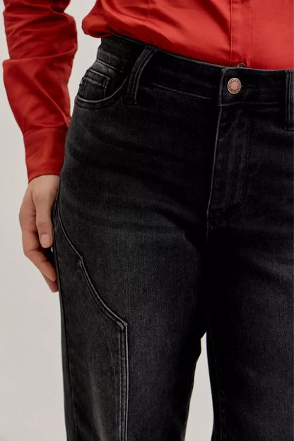 Close-up of black high-waisted jeans with a curved pocket, styled with a red blouse