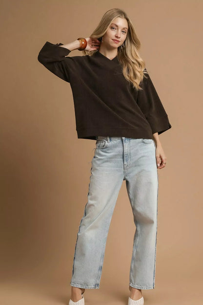 Woman wearing a relaxed-fit chocolate brown sweater, light wash wide-leg jeans, and heels