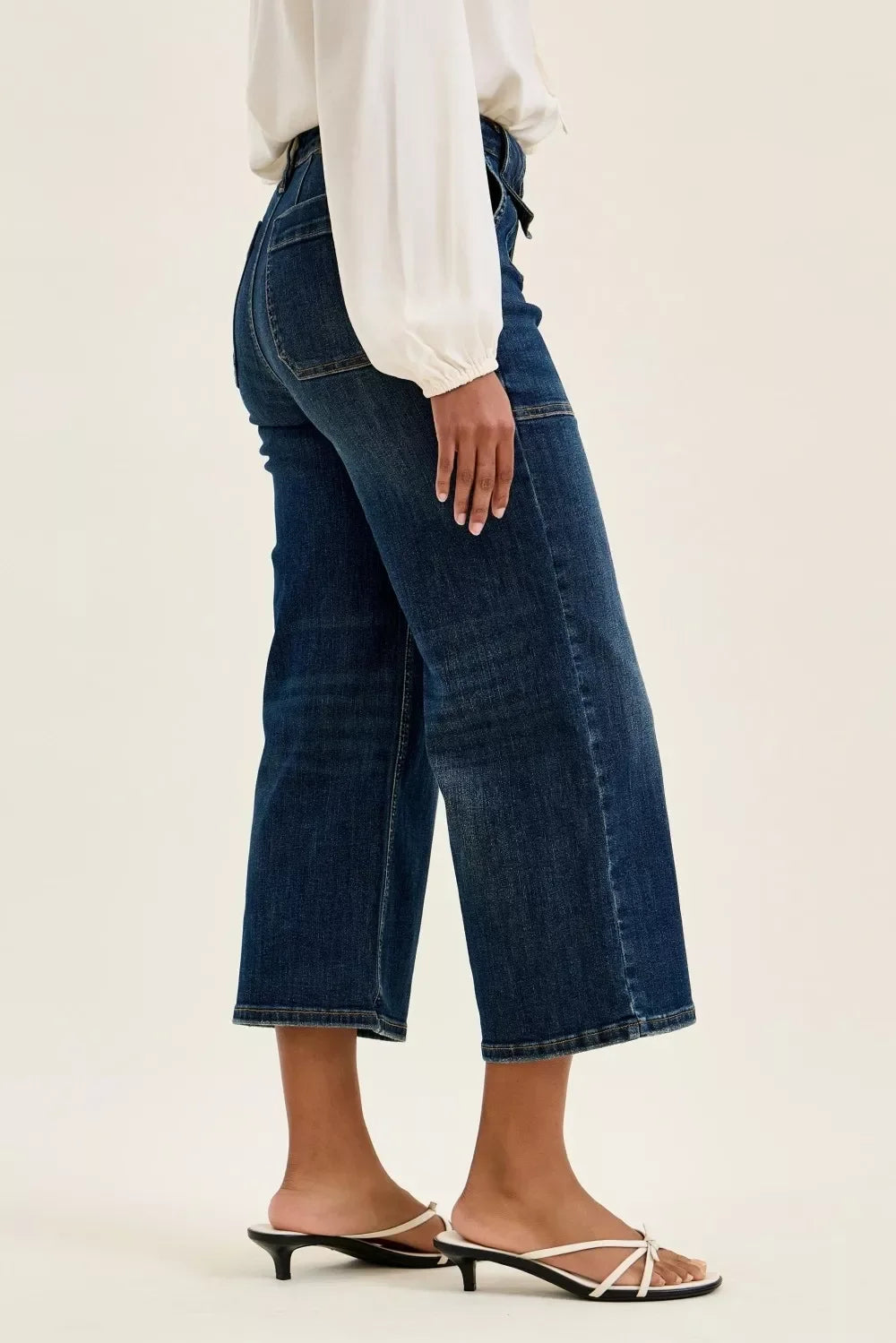 Woman wearing wide-leg cropped denim jeans with a white blouse and heeled sandals