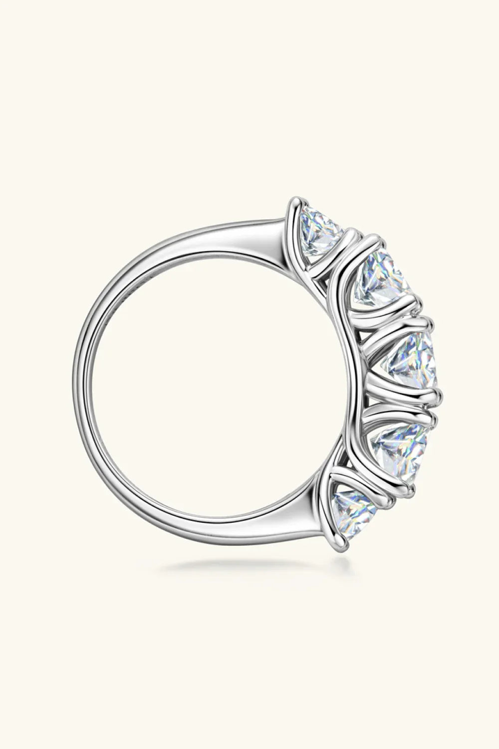Silver band ring with five round-cut clear gemstones in prong settings, side view