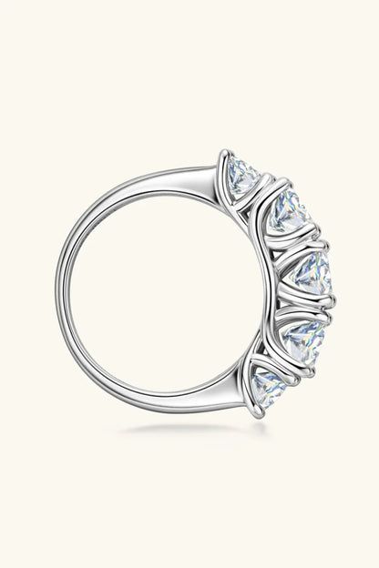 Silver band ring with five round-cut clear gemstones in prong settings, side view