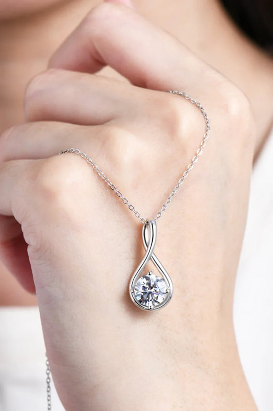 Elegant silver infinity pendant necklace with round gemstone, shown on a woman's hand