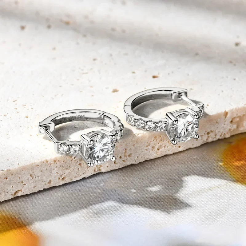 Silver hoop earrings with round cut crystals and pavé accents on stone surface