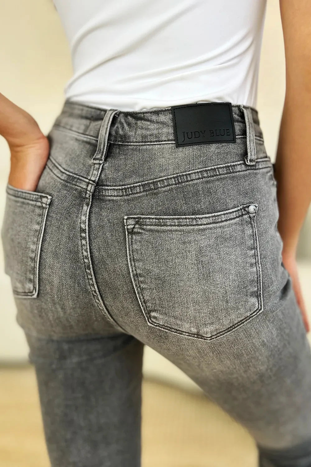 Close-up of woman wearing high-waisted grey washed jeans with back pockets