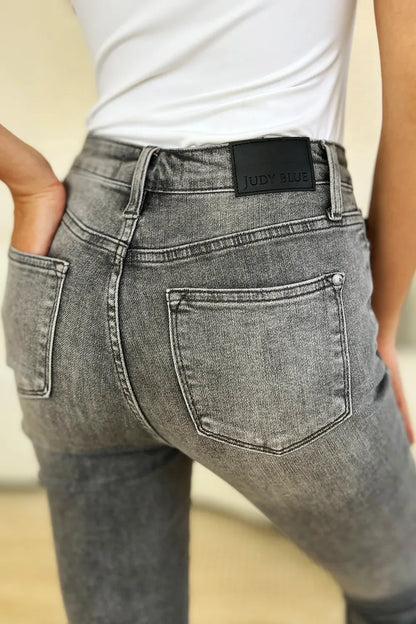 Close-up of woman wearing high-waisted grey washed jeans with back pockets