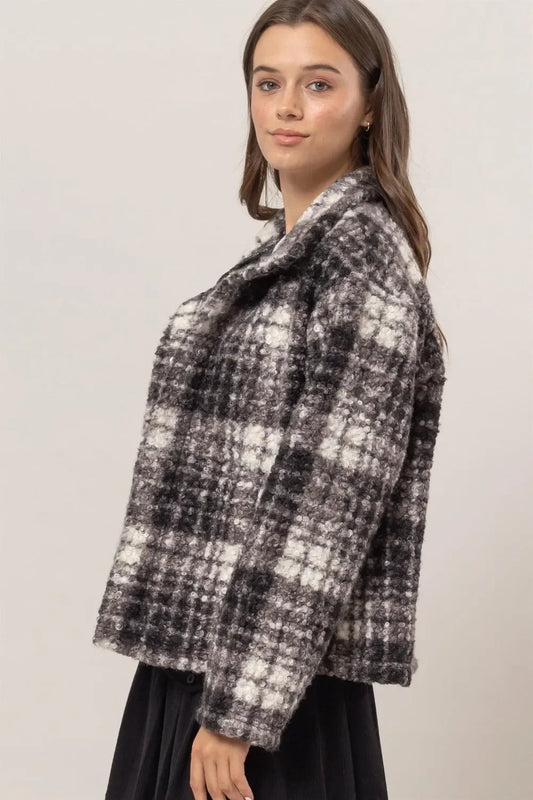Woman wearing black and white plaid textured jacket with relaxed fit and wide collar