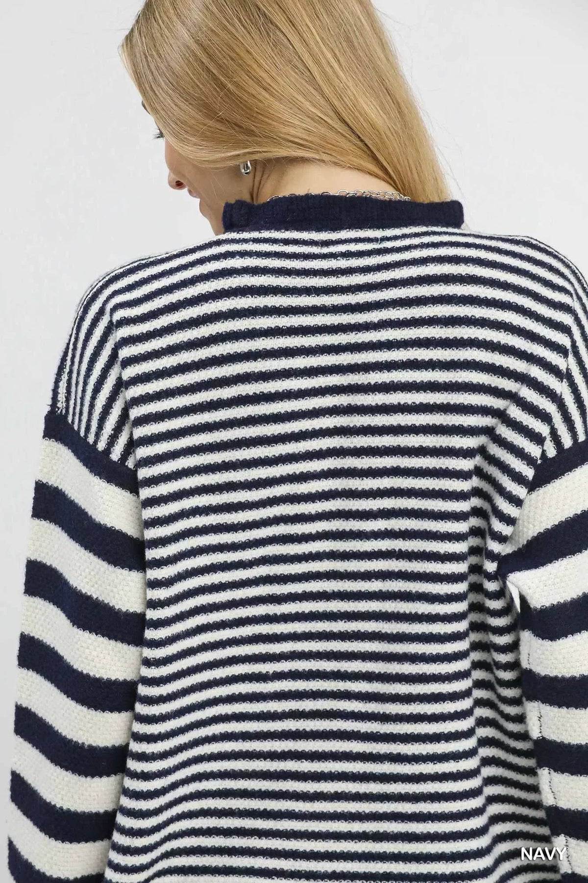 Back view of woman wearing navy and white striped knit sweater, blonde hair, casual style