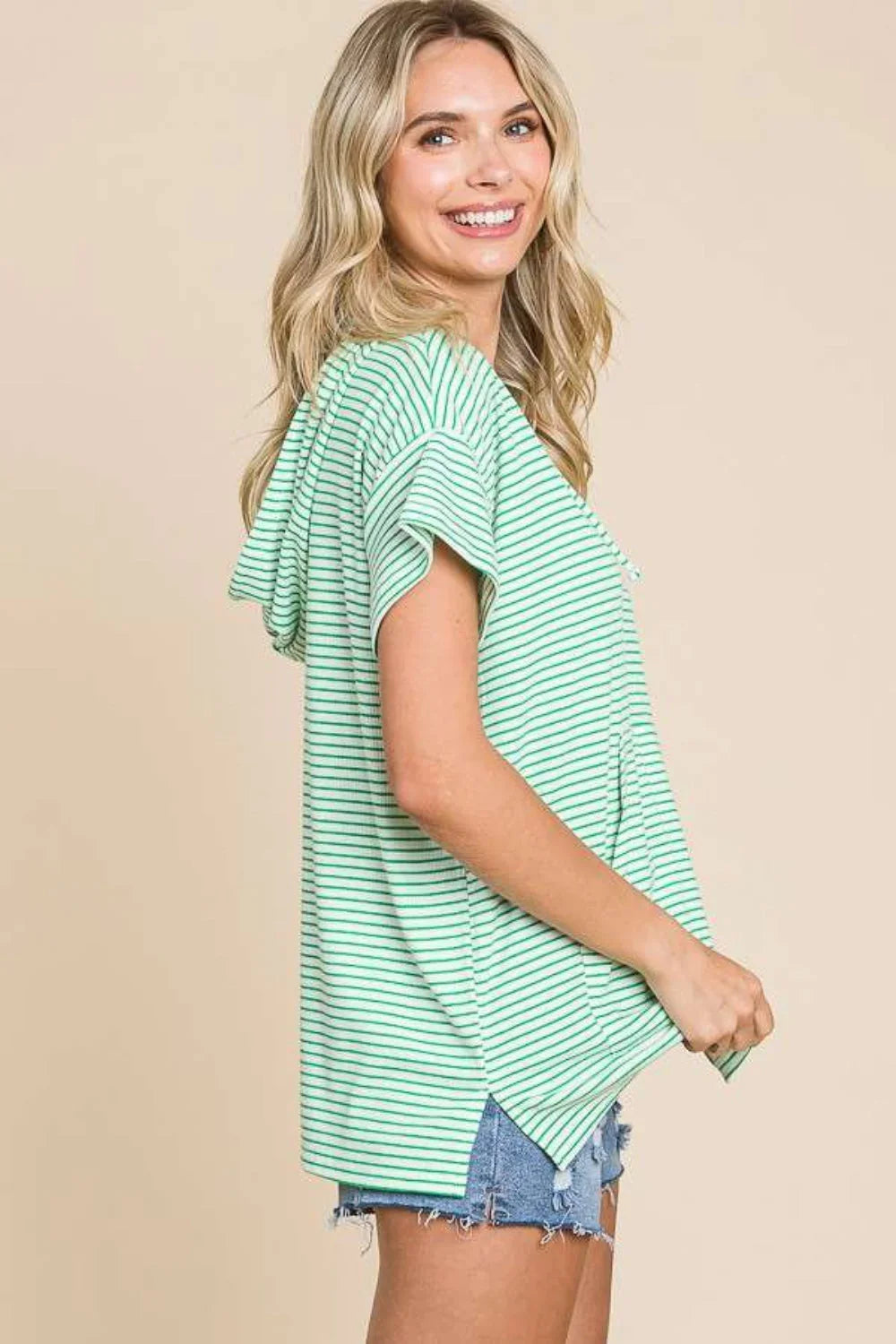 Woman in mint green striped short-sleeve hoodie and denim shorts, side view