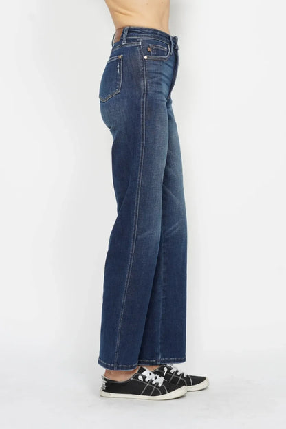 Side view of woman wearing high-waisted wide-leg blue jeans and black sneakers