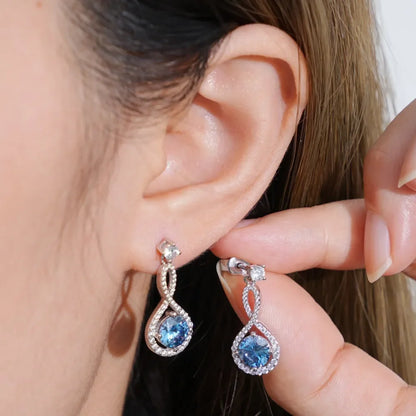 Woman wearing elegant silver drop earrings with blue gemstones and crystal accents