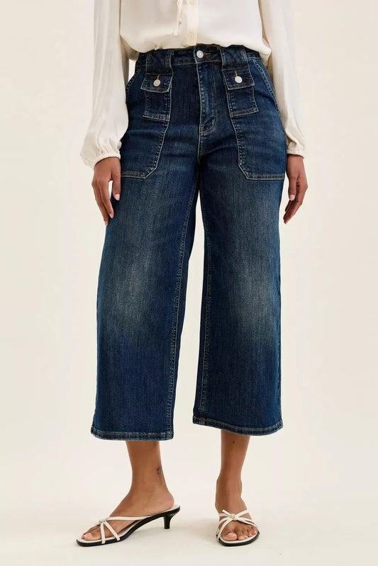 Woman wearing wide-leg cropped dark denim jeans with patch pockets and button accents