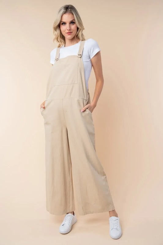 Woman wearing beige wide-leg overalls with a white t-shirt and white sneakers