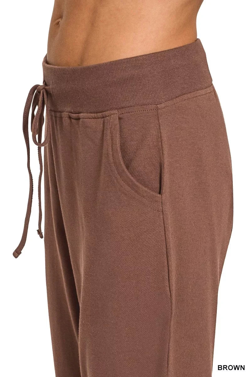Close-up of brown women’s jogger pants with an elastic waistband, drawstring, and side pocket.